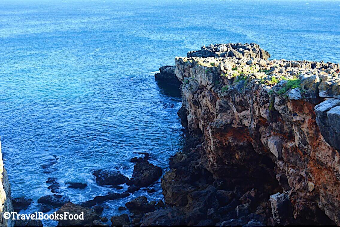 This is a photo of some rocks and the sea at the Cascais beach in Portugal