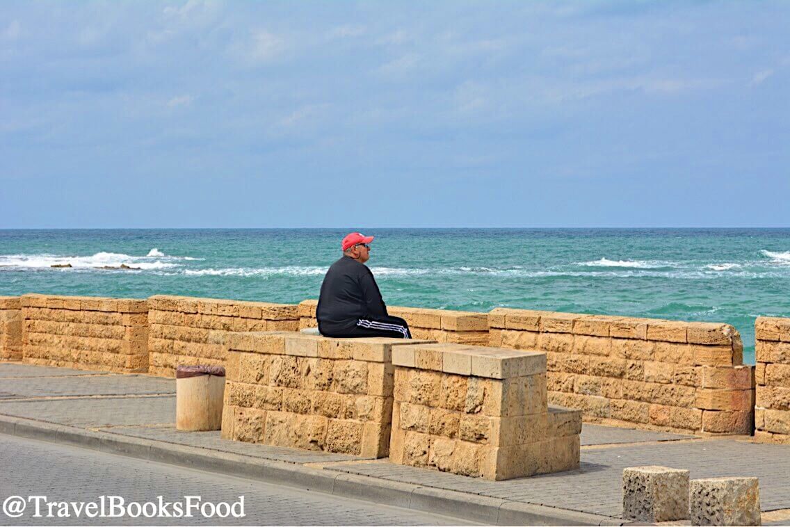 A lone man staring into the Ocean along the Tel Aviv Promenade