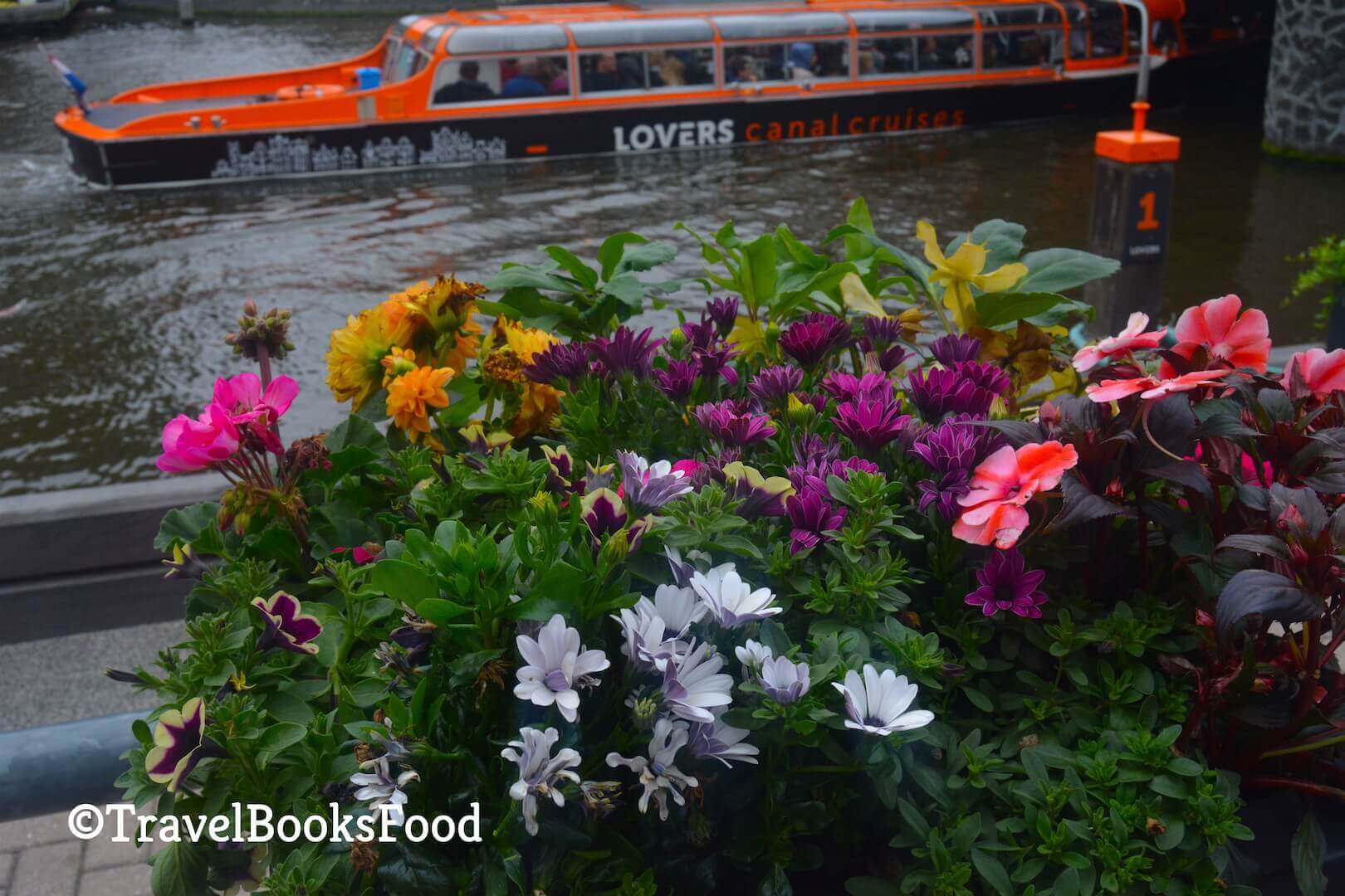 Flower basket overlooking a canal cruise boat in Amsterdam Canals