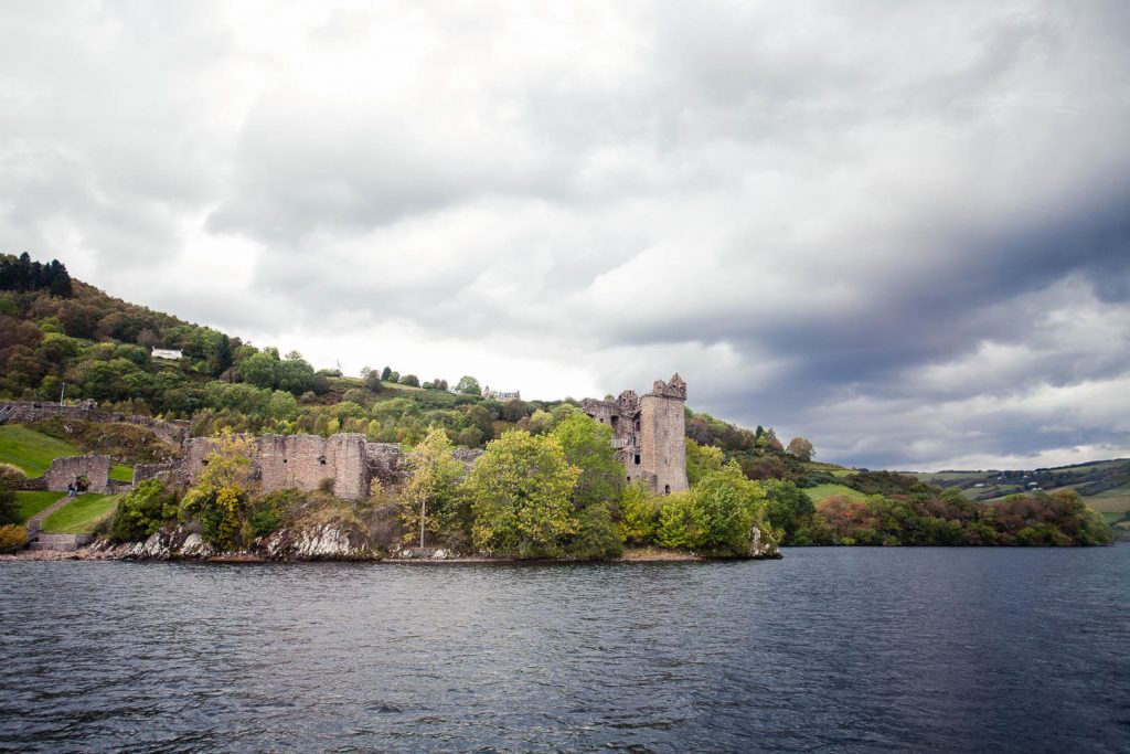 A castle as seen from the middle of a lake surrounded by greenery
