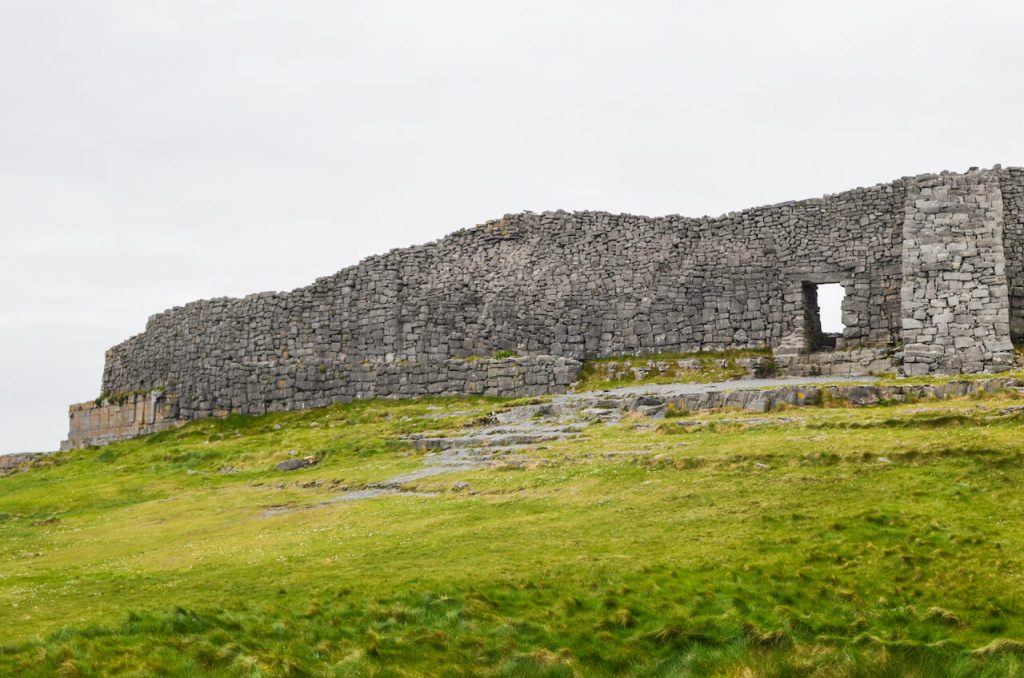 A picture of a stone wall against a green field