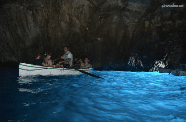 A picture of a boat in a cave with blue water