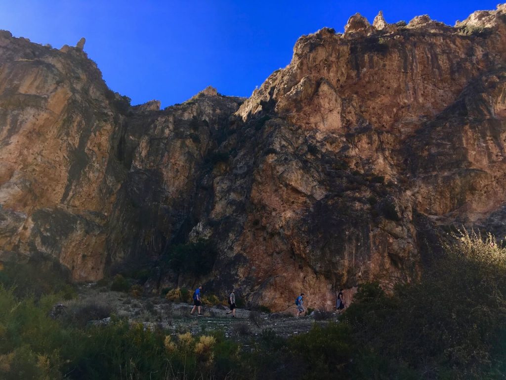 A photo of a brown mountain with some people hiking