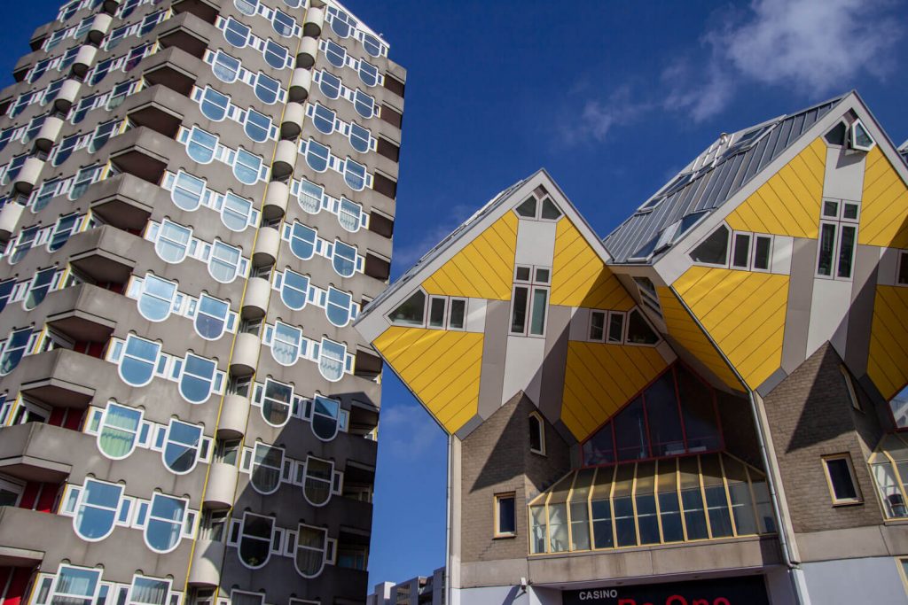 A picture of the yellow cube houses in Rotterdam next to a cylindrical building