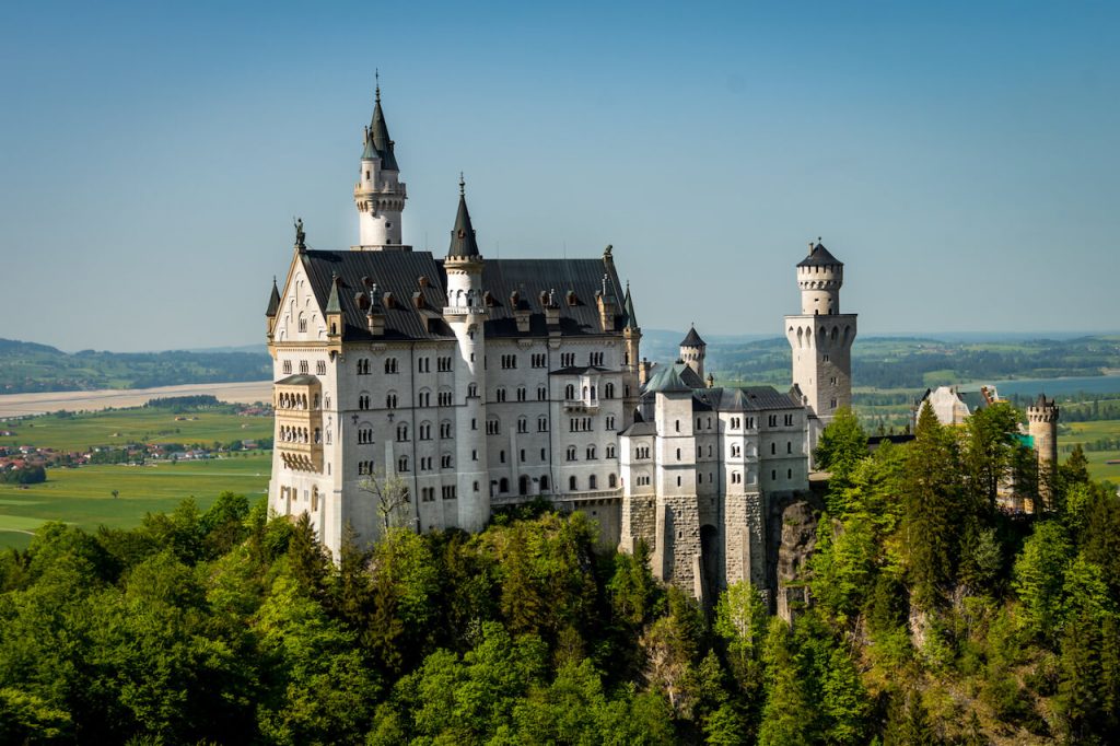 Picture of the Neuschwanstein castle from a distance on top of a hilltop