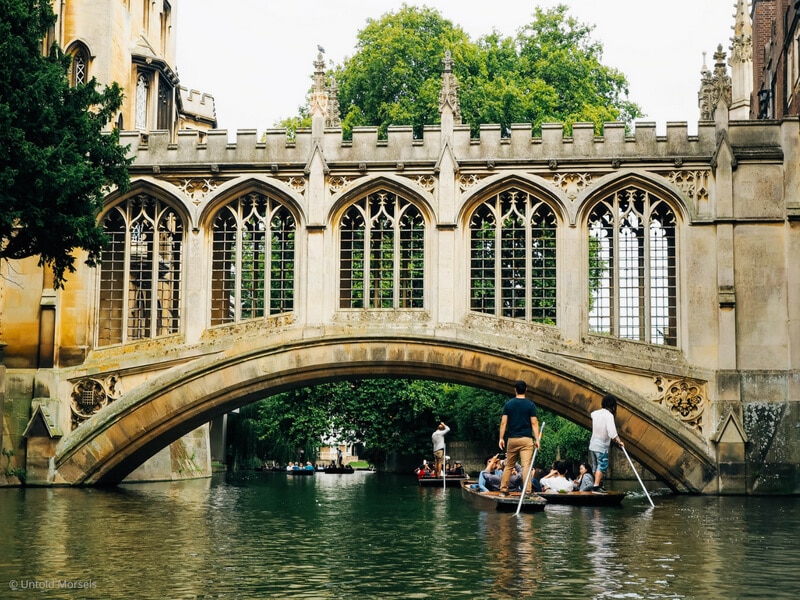 A phot of a bridge as seen from a canal with lots of small boats