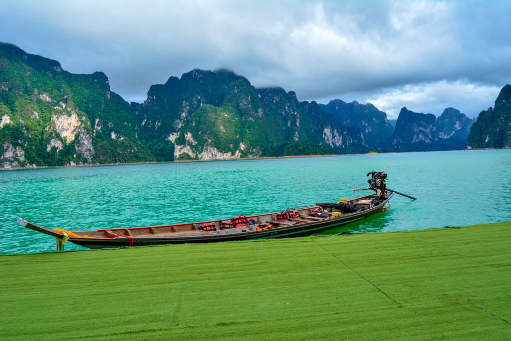 A boar across some gorgeous mountains and a green lake